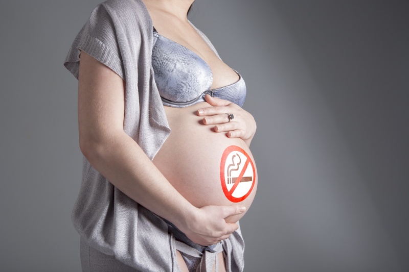 Op deze foto ziet u een zwangere vrouw met een 'stoppen met roken' logo op haar buik geschilderd.